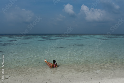 Young woman on tropical beach with cloudy sky and clear water