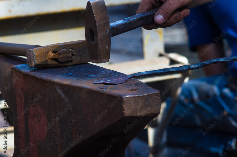 blacksmith performs the forging of hot glowing metal on the anvil blacksmith performs the forging of hot glowing metal on the anvil