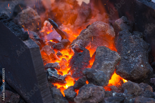 blacksmith furnace with burning coals, tools, and glowing hot metal workpieces