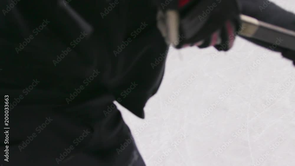 Slow motion action shot looking down the arms and stick of a hockey player as he takes a wrist shot on an outdoor rink Slow motion action shot looking down the arms and stick of a hockey player as he takes a wrist shot on an outdoor rink