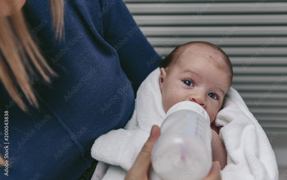 Newborn baby girl taking feeding bottle in her mother's arms Newborn baby girl taking feeding bottle in her mother's arms