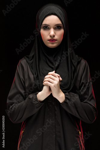 Bild auf Leinwand Beautiful young woman wearing black hijab as conservative fashion concept on bla