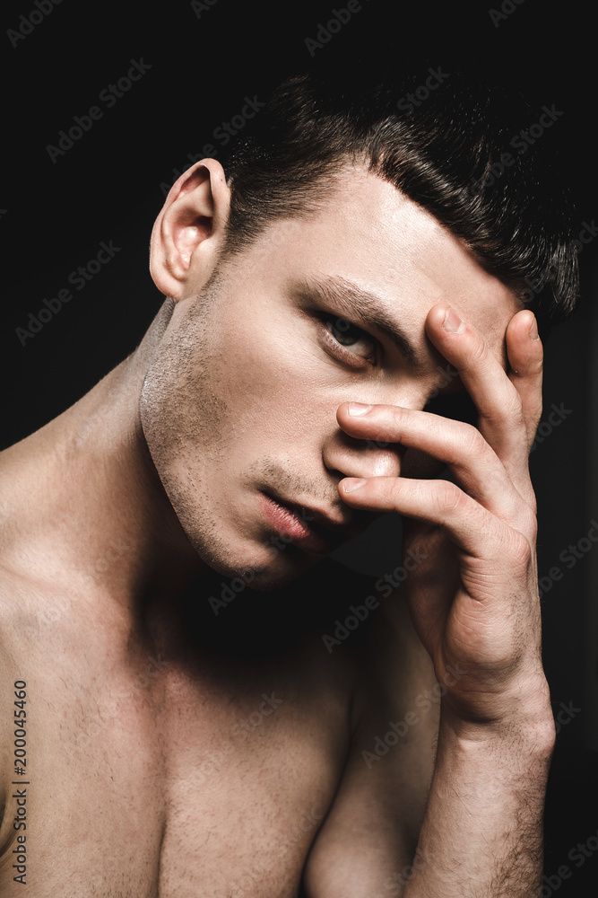 Orderly male looking at camera while closing face by arm. Handsome dude showing seriousness concept Orderly male looking at camera while closing face by arm. Handsome dude showing seriousness concept