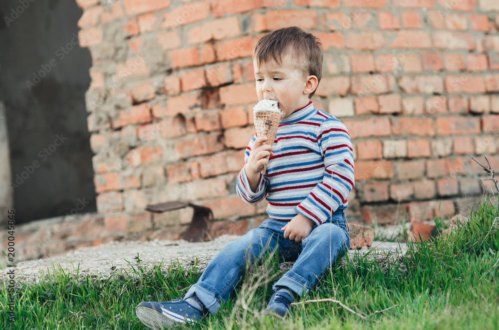 little cute boy eating ice cream three years very appetizing, amid nature, green grass little cute boy eating ice cream three years very appetizing, amid nature, green grass