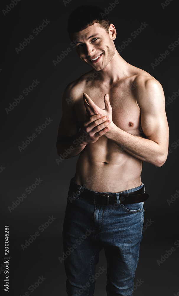 Fototapeta premium Portrait of cheerful man with brilliant smile and attractive body crossing hands. Happy bare-chested guy concept. He isolated on black background