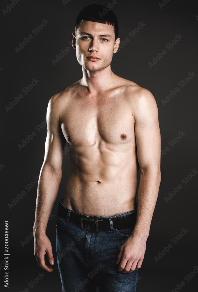 Portrait of serene young bare-chested man isolated on dark background. Calm guy with attractive body concept Portrait of serene young bare-chested man isolated on dark background. Calm guy with attractive body concept