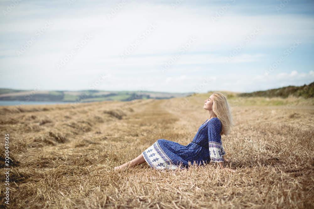 Side view of young woman sitting in field Side view of young woman sitting in field