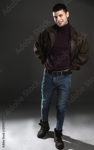 Full length portrait of happy man concealing arms with jacket. Gladness concept