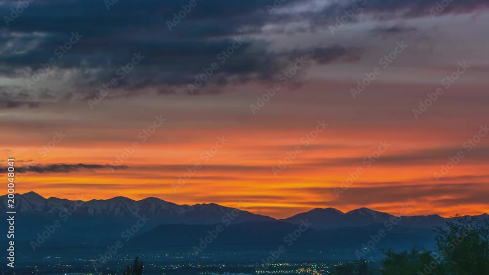Time lapse of a beautiful golden sunset as the camera zooms out to wide angle to reveal the sky along theRocky Mountain range and the city in the valley Time lapse of a beautiful golden sunset as the camera zooms out to wide angle to reveal the sky along theRocky Mountain range and the city in the valley