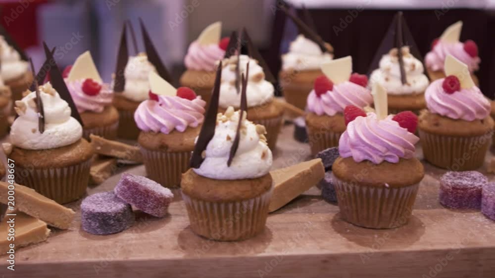A panning shot across many cupcakes and other desserts. A panning shot across many cupcakes and other desserts.