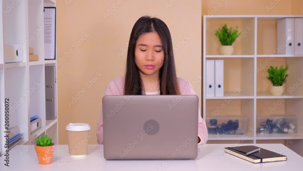 asian young woman in the modern contemporary office. attractive young worker in startup company sitting at the white desk typing on computer. businesswoman looking at the camera with happy friendly asian young woman in the modern contemporary office. attractive young worker in startup company sitting at the white desk typing on computer. businesswoman looking at the camera with happy friendly