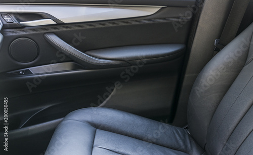 Modern luxury car black perforated leather interior. Part of leather car seat details. Modern car interior details. Car detailing. Door handle © Aleksei