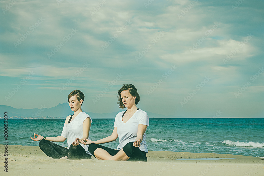 Girls practicing yoga on the beach Girls practicing yoga on the beach