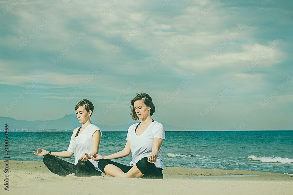 Girls practicing yoga on the beach