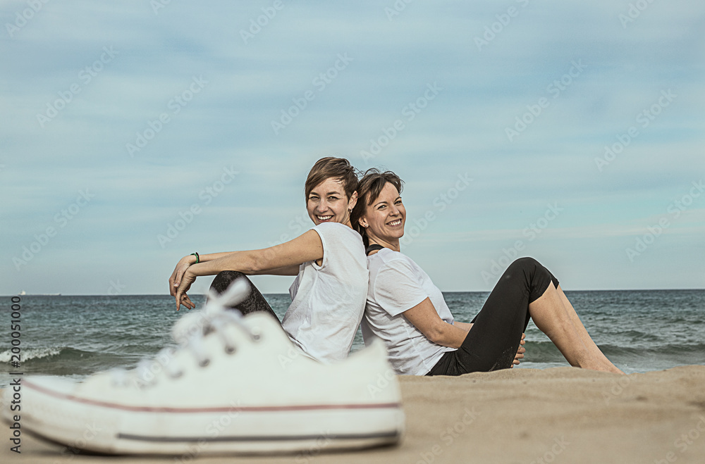 Normal women on the beach smiling and sitting on the sand.