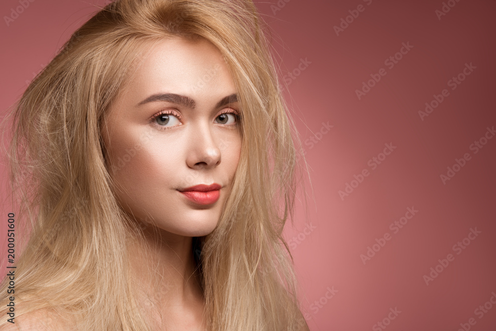 Fototapeta premium Portrait of sad lady with disheveled hair looking at camera. Copy space in right side. Isolated on rose background