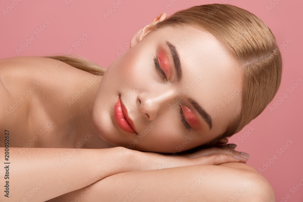 Portrait of attractive calm lady with naked torso resting on her hands with eyes closed. Isolated on rose background Portrait of attractive calm lady with naked torso resting on her hands with eyes closed. Isolated on rose background