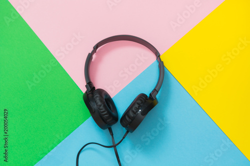 Modern style black headphones on colorful background.