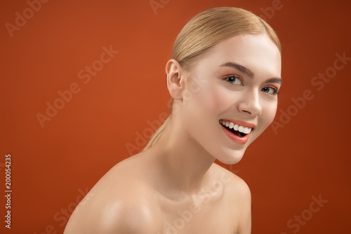 Portrait of content nude girl with well cared pure pelt. She is staring at camera and laughing. Isolated on background