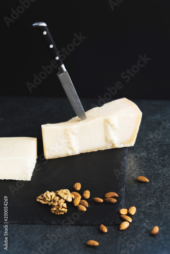 An appetizing solid cheese on a black plate on a gray stone background photo