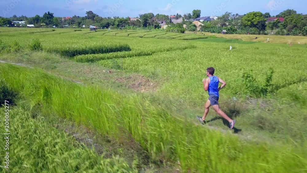 Aerial shot with drone tracking young fit runner man in running off road workout on a sunny morning in sport practice and healthy lifestyle concept Aerial shot with drone tracking young fit runner man in running off road workout on a sunny morning in sport practice and healthy lifestyle concept
