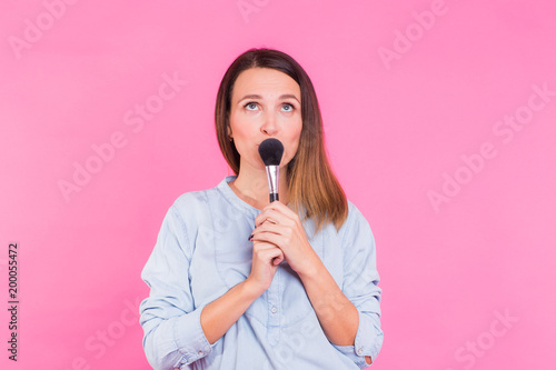 Excited beauty makeup artist. Beautiful young woman pretty smiling funny fashion girl holding eyeshadow brushes on pink background