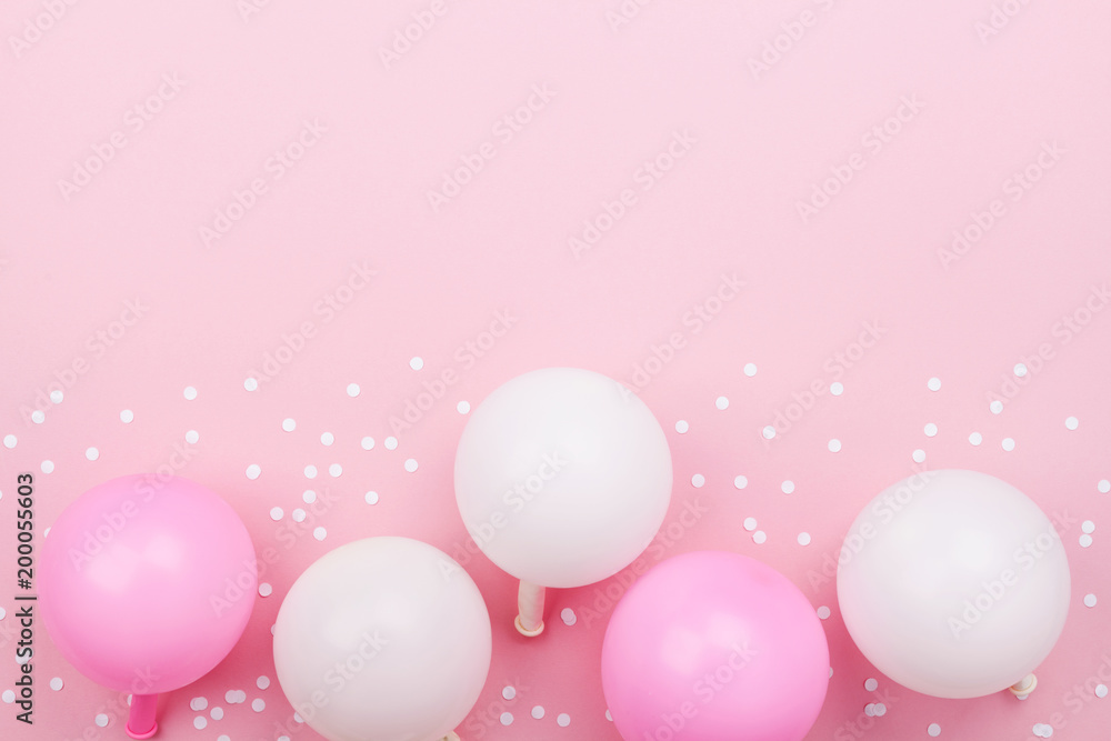 Pastel pink table with balloons and confetti for birthday top view. Flat lay style.
