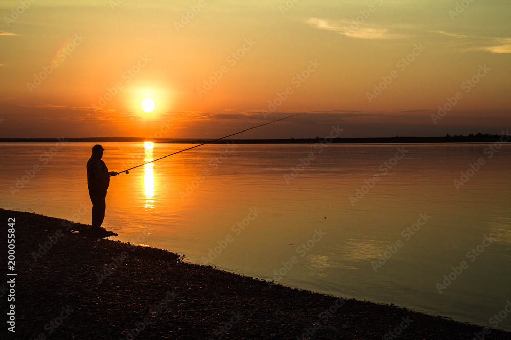  Silhouettes of fishermen against the background of a colorful sunset.