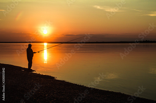 Silhouettes of fishermen against the background of a colorful sunset.