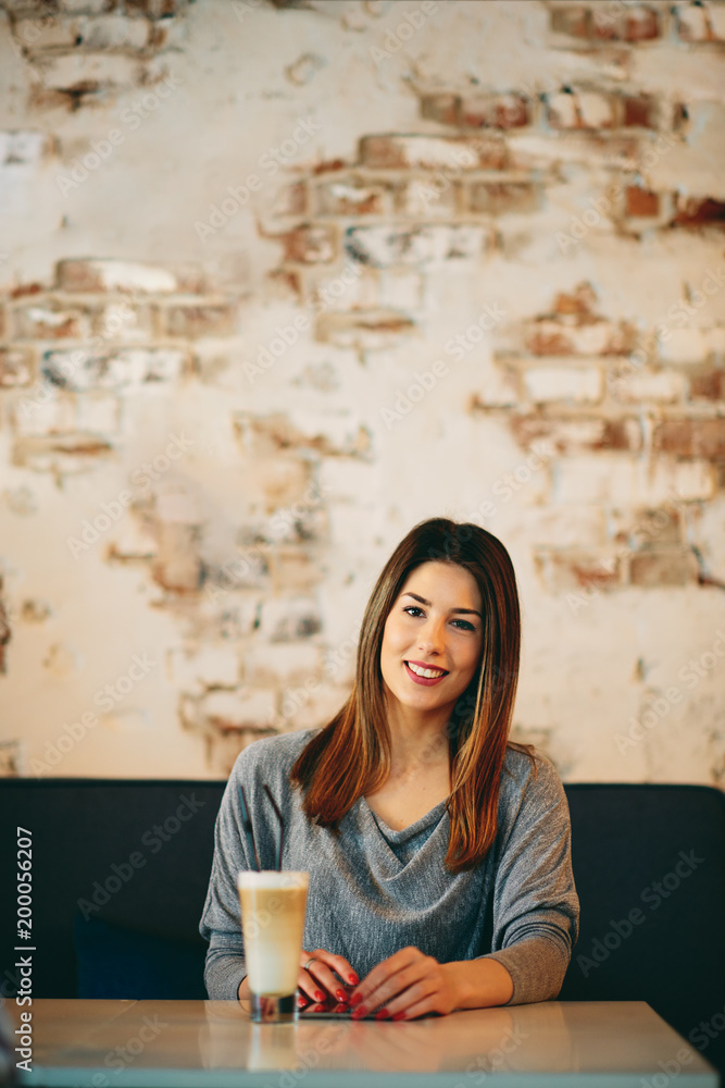 Young caucasian woman using tablet while sitting in cafe and drinking coffee. Young caucasian woman using tablet while sitting in cafe and drinking coffee.