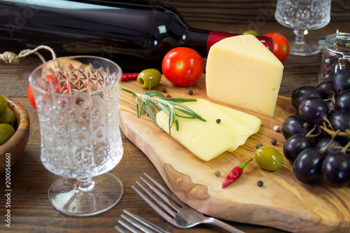 Grape cheese and vegetables on the chopping board.Healthy diet. Crystal glass and cheese in focus