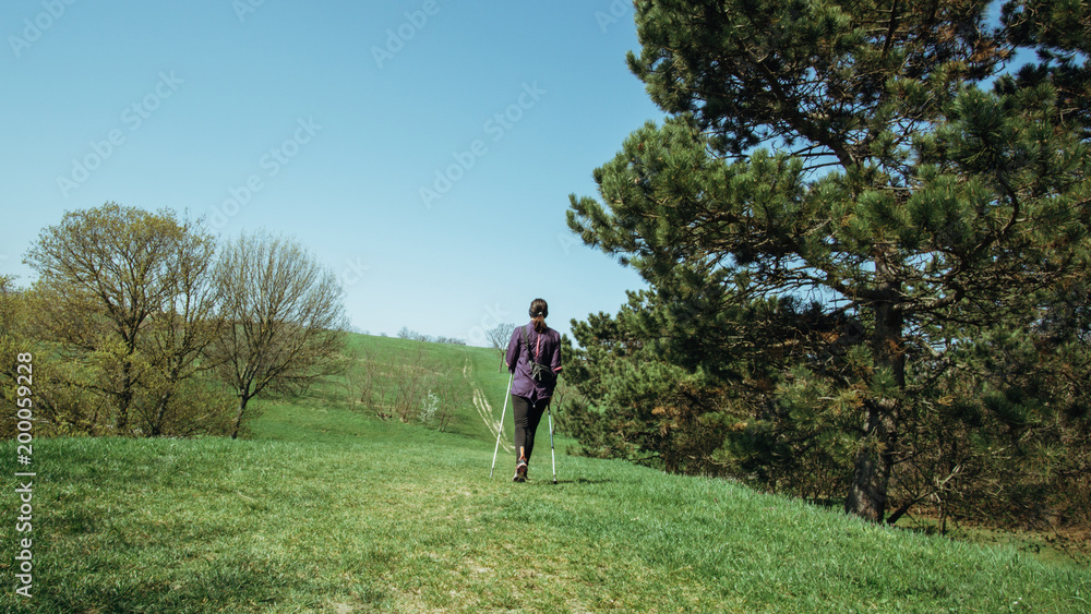 Nordic walking - Frau wandert Hügel hinauf Nordic walking - Frau wandert Hügel hinauf