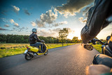 Motor biker riding on empty road with sunset light, concept of speed and touring in nature.