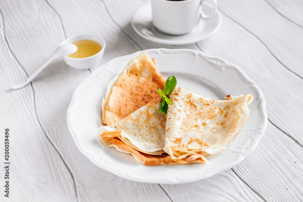 Breakfast pancakes with honey and tea on a white wooden table Breakfast pancakes with honey and tea on a white wooden table
