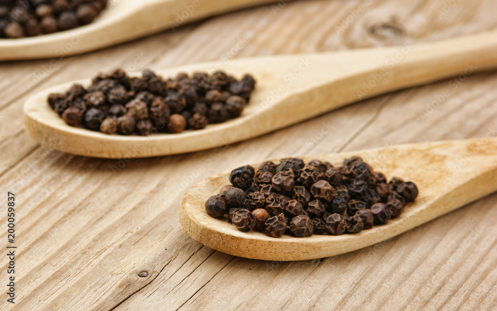 Black pepper in wooden spoon on the old board Black pepper in wooden spoon on the old board