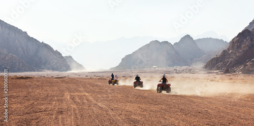high speed race of several people riding quad bikes in desert photo