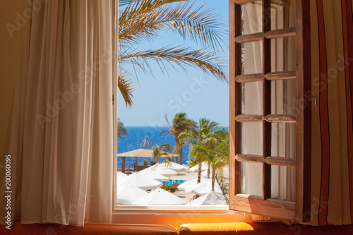 empty tropical resort background, out of window view with palm trees, sea and tents