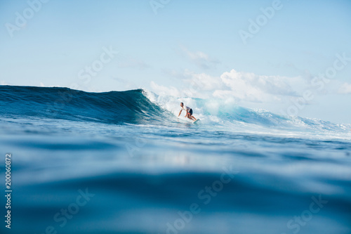 handsome athletic man surfing on blue wave