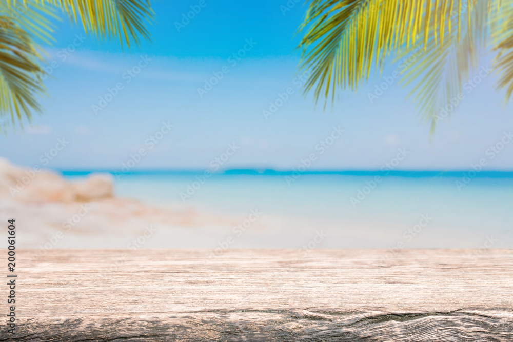 Empty wood table top and blurred Palm tree summer beach with blue sea and sky background. - can used for display or montage your products.