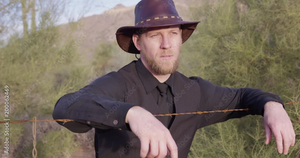 American cowboy leaning on barbwire fence at sunset? American cowboy leaning on barbwire fence at sunset?