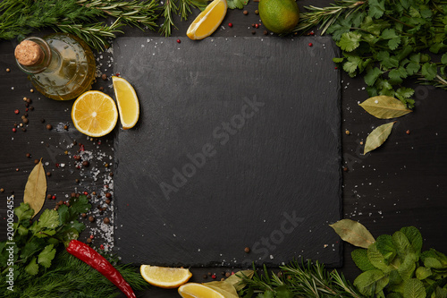 Black slate board with fresh herbs and lemon slices with olive oil photo