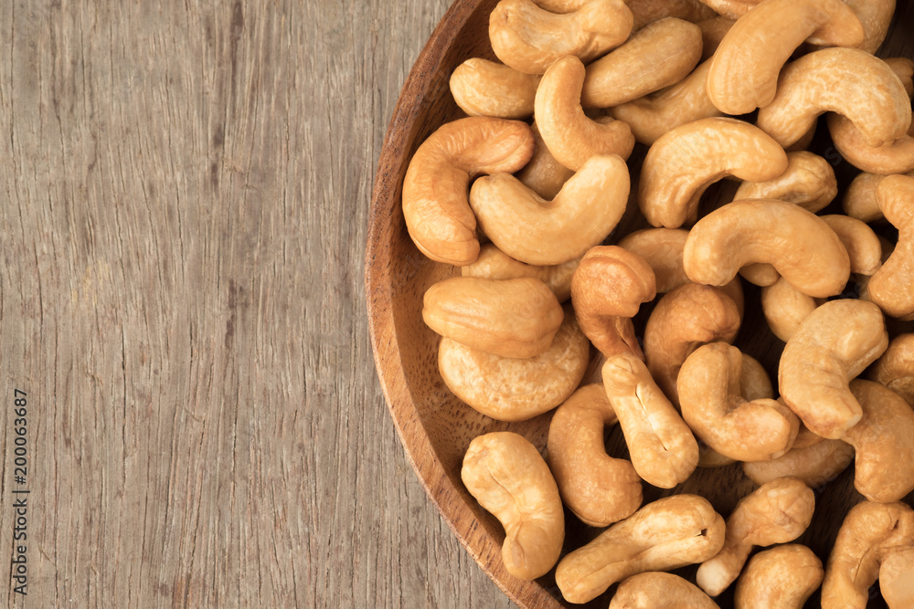 Cashew nuts in wooden bowl on woden table. Cashew nuts in wooden bowl on woden table.