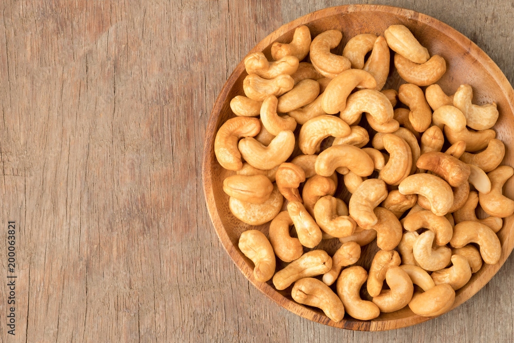 Cashew nuts in wooden bowl on woden table. Cashew nuts in wooden bowl on woden table.