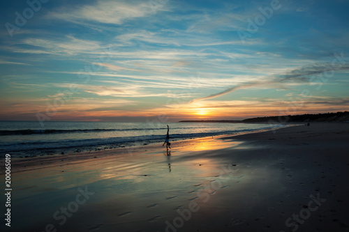 Sunset overlooking a beach in Normandy  France  with a girl doing a handstand.