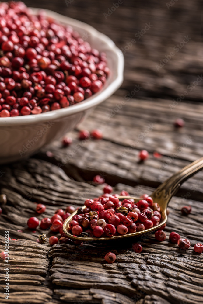 Red peppercorn in bowl and spoon on oak table Red peppercorn in bowl and spoon on oak table