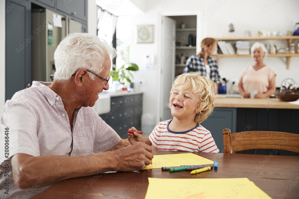 Obraz premium Grandad and grandson drawing together in family kitchen, close up
