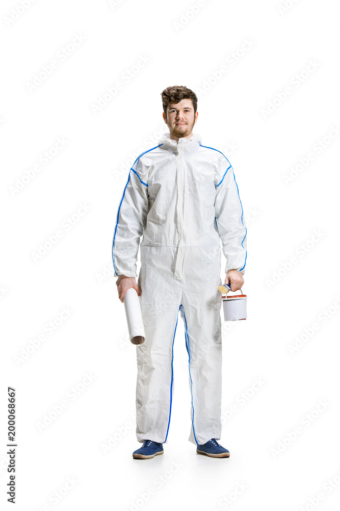 Young male decorator painting with a paint roller climbed a ladder isolated on white background. Young male decorator painting with a paint roller climbed a ladder isolated on white background.