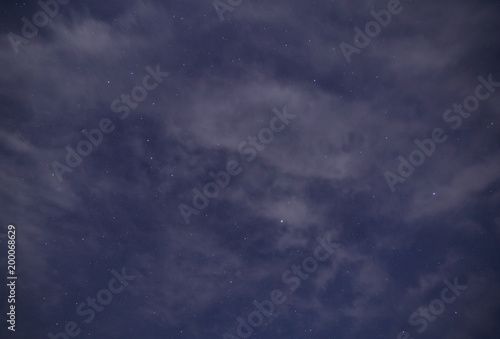 view on cloudy sky with stars at night © romantiche