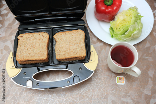 Śniadanie z tostów robionych w tosterze, sałaty, papryki i herbaty owocowej.