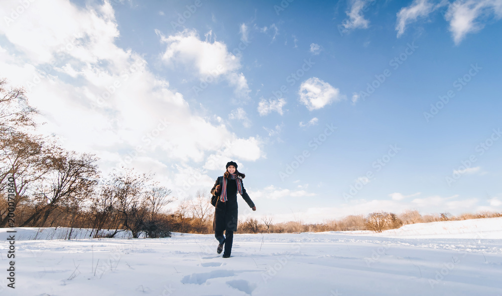 Obraz premium Young pretty girl tourist with backpack goes through the snowy forest, the concept of a healthy lifestyle and outdoor activities in winter walks.